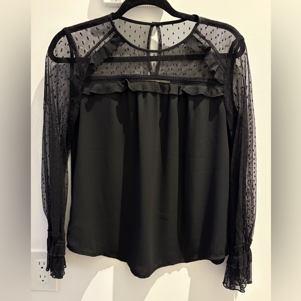 Black blouse with sheer polka dot sleeves and neckline.